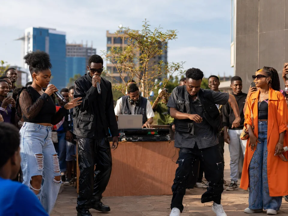 People with microphones gathered around a laptop and sound equipment outdoors.